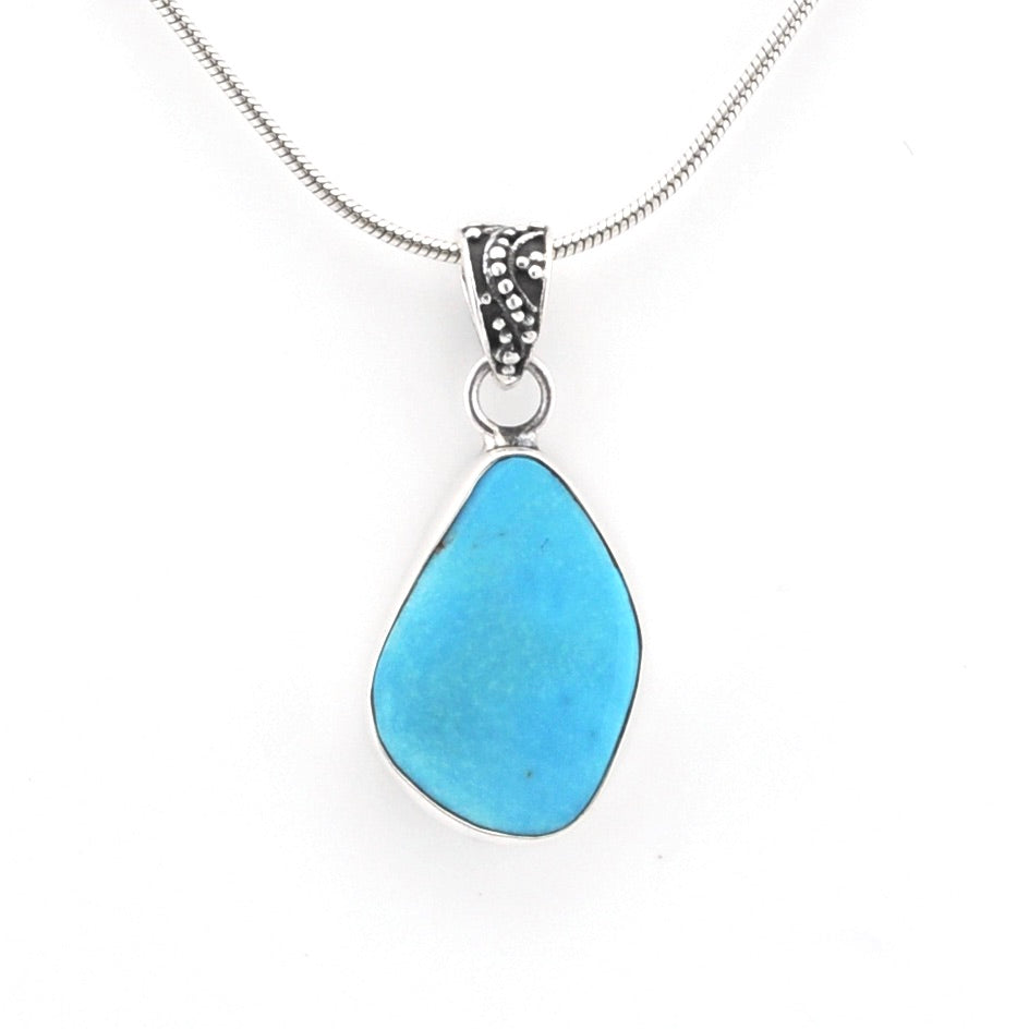 A silver necklace featuring a teardrop-shaped light blue turquoise stone pendant, suspended from a delicate silver chain against a plain white background.