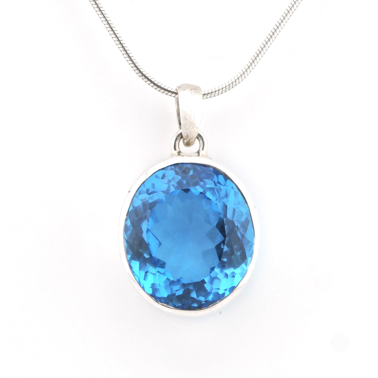 A round-cut blue gemstone pendant in a silver bezel setting on a silver snake chain, shown against a plain white background.