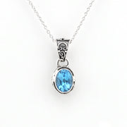A silver pendant necklace featuring an oval-cut light blue gemstone in a silver bezel setting, suspended from a delicate silver chain against a plain white background.