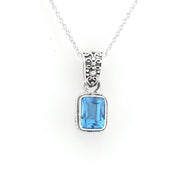A silver pendant necklace featuring a rectangular light blue gemstone in a silver bezel setting with an ornate filigree bail, suspended from a delicate silver chain against a plain white background.