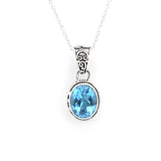 A silver pendant necklace featuring an oval-cut light blue gemstone in a silver bezel setting, suspended from a delicate silver chain against a plain white background.