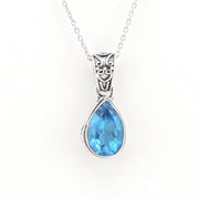 A silver pendant necklace featuring a faceted teardrop-shaped light blue gemstone in a silver bezel setting, suspended from a delicate silver chain against a plain white background.