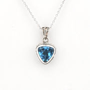 A silver pendant necklace featuring a faceted triangular blue gemstone in a silver bezel setting, suspended from a delicate silver chain against a plain white background.