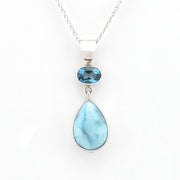A silver pendant necklace featuring a teardrop-shaped light blue larimar stone and a smaller oval blue topaz stone, displayed on a clean white background.