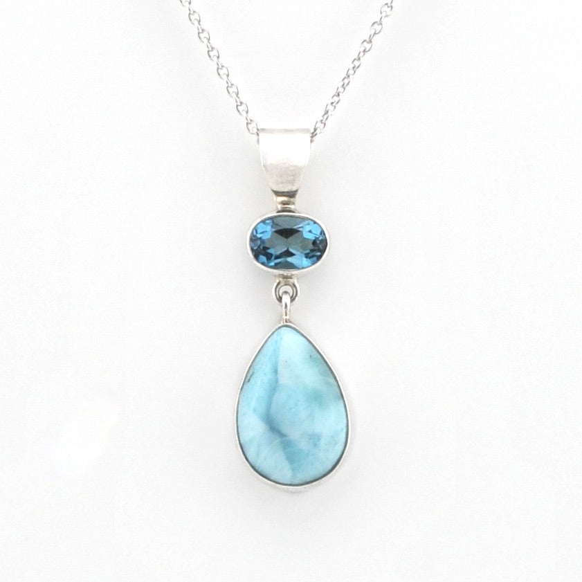 A silver pendant necklace featuring a teardrop-shaped light blue larimar stone and a smaller oval blue topaz stone, displayed on a clean white background.