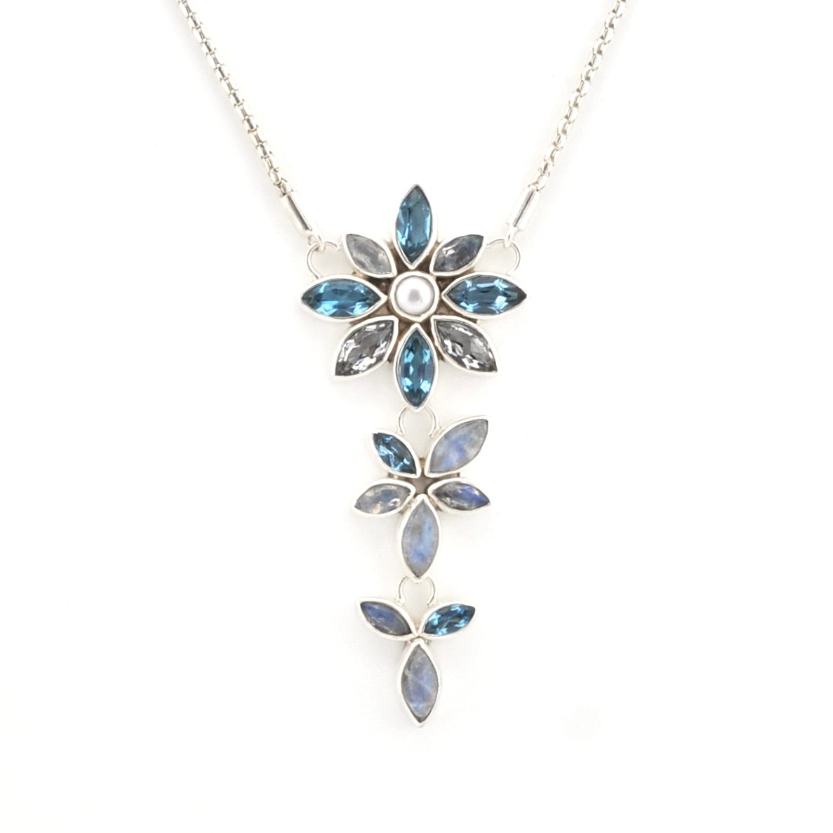 A silver-tone floral dangle necklace featuring three cascading flower pendants with marquise-cut blue gemstones and a central round clear stone on a white background.