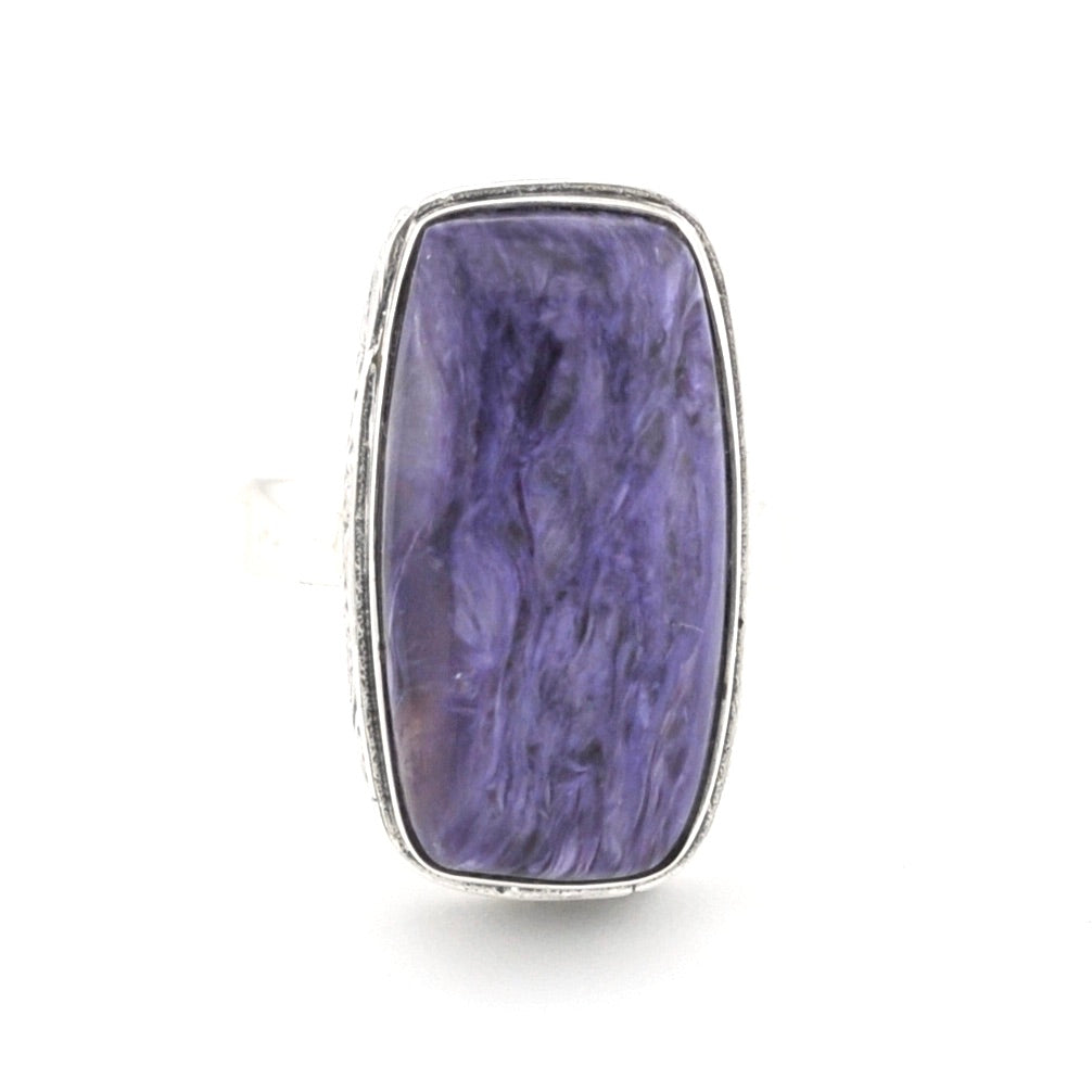 A rectangular silver ring featuring a large, polished purple stone with natural marbled patterns, set against a plain white background.