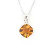 A silver necklace with a cushion-cut orange gemstone pendant, displayed against a solid white background.