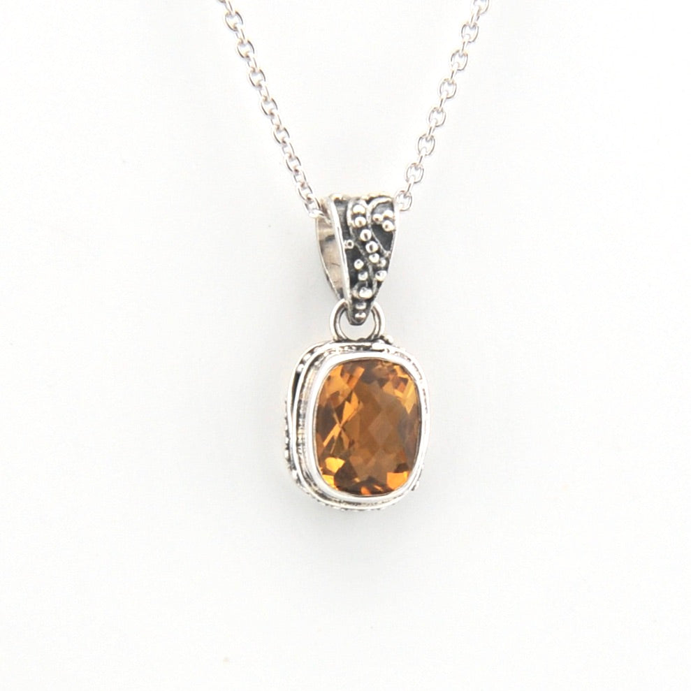 Silver pendant with a yellow gemstone on a white background