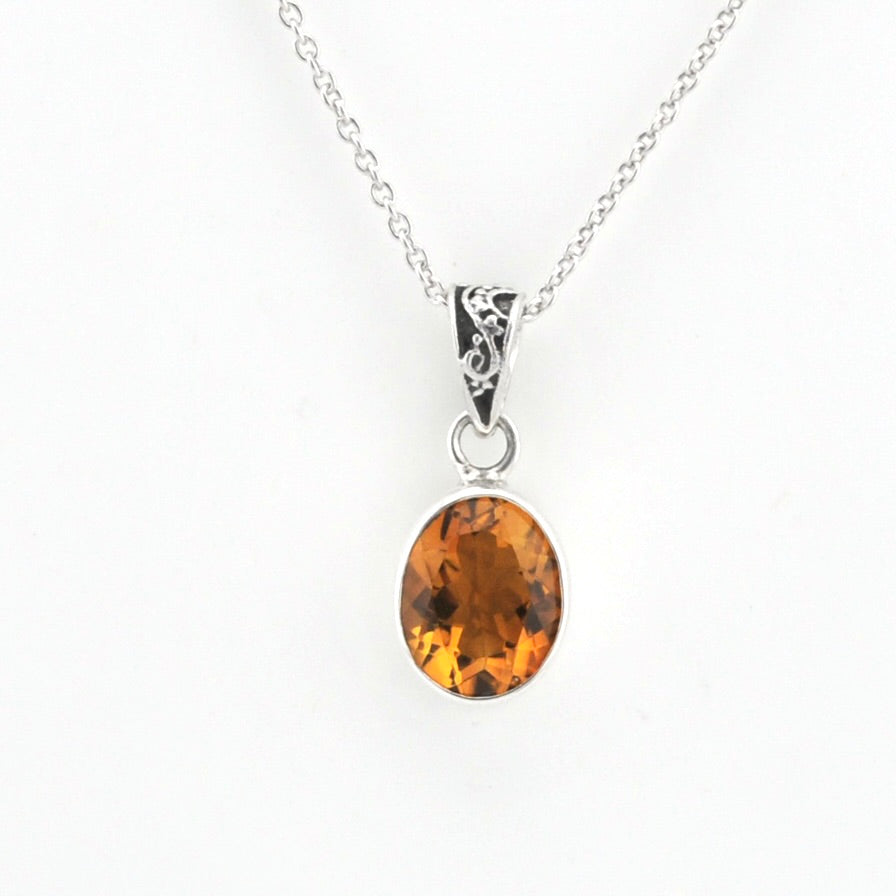An oval citrine gemstone pendant necklace in a silver bezel setting on a delicate silver chain, shown against a plain white background.