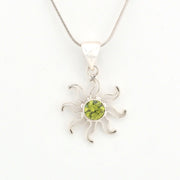 Silver sun-shaped pendant with a green gemstone on a white background