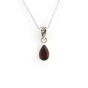 A silver teardrop pendant necklace featuring a faceted dark red gemstone, suspended from a delicate silver chain against a plain white background.