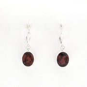 A pair of silver drop earrings with oval dark reddish-brown gemstones, shown on a plain white background.
