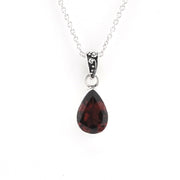 A silver teardrop pendant necklace featuring a faceted dark red gemstone, suspended from a delicate silver chain against a plain white background.