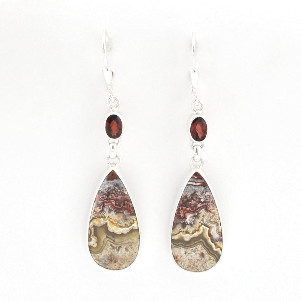 A pair of teardrop-shaped dangle earrings featuring natural agate stone inlays with earthy brown, beige, and gray banding, accented by small round dark red garnet beads on silver hooks, set against a plain white background.