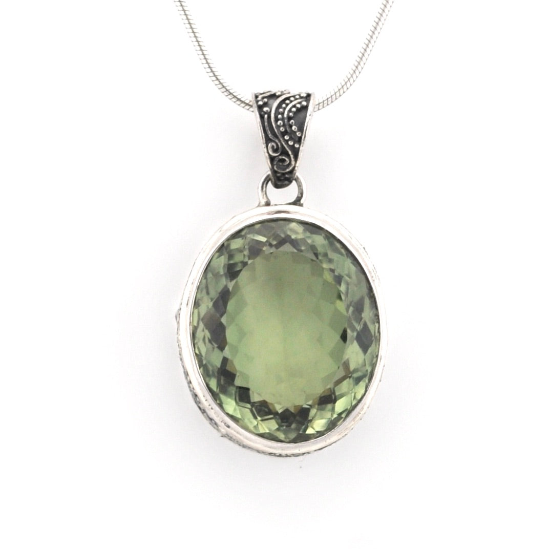 An oval-cut green gemstone pendant in a silver bezel setting on a silver chain, shown against a plain white background.