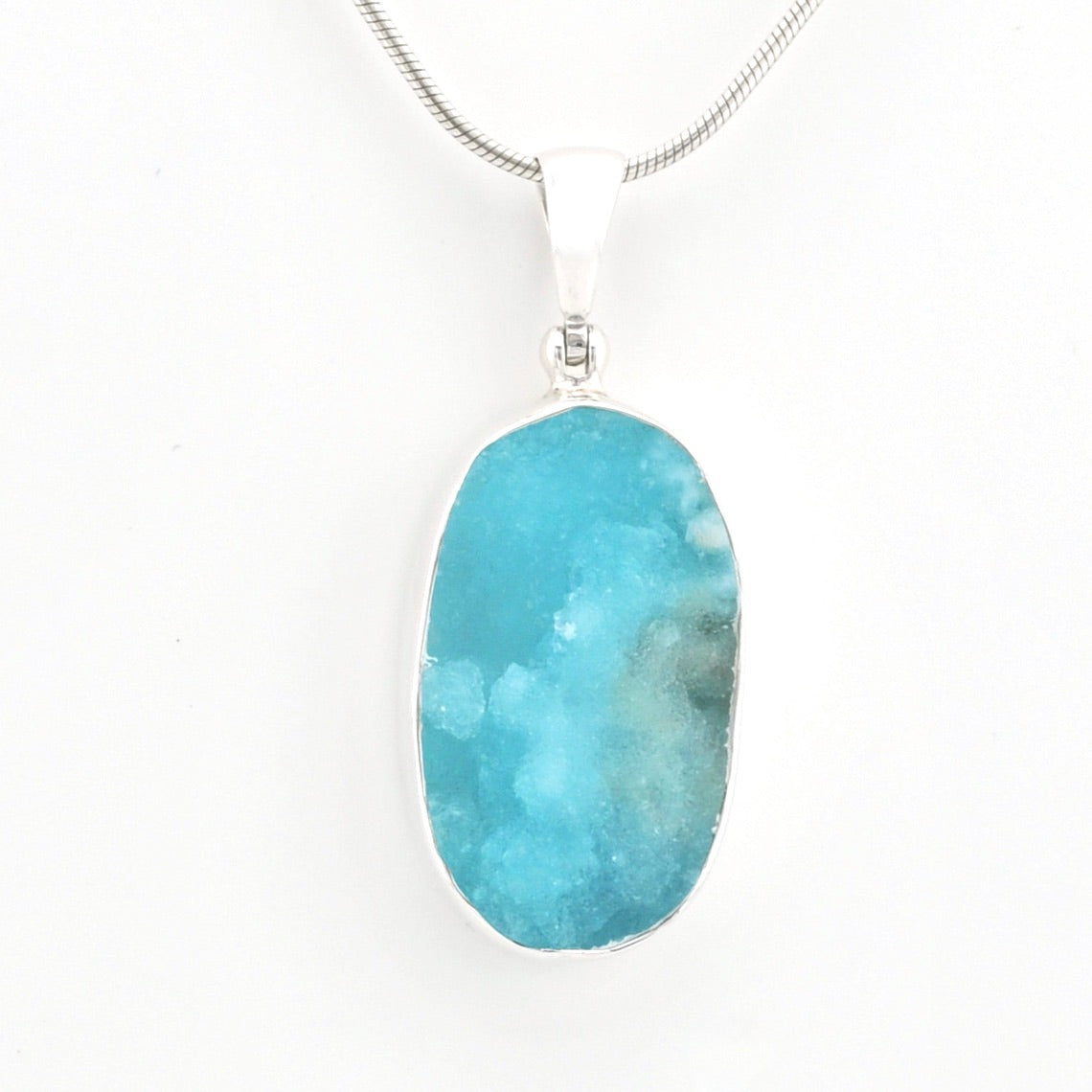 A silver pendant necklace featuring a oval hemimorphite stone with natural druzy patterns, suspended from a silver snake chain against a plain white background.