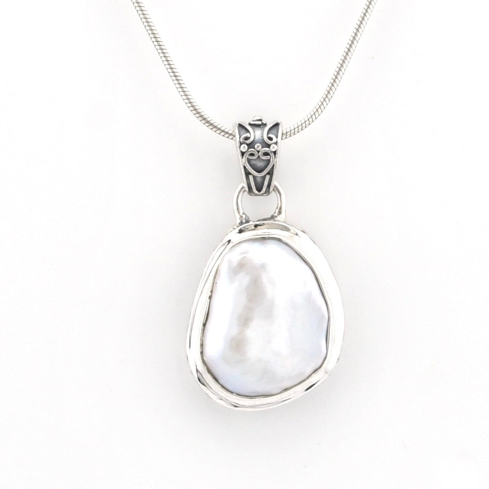 A sterling silver pendant necklace featuring a large, irregularly shaped white mother-of-pearl bead set in a polished silver bezel, suspended from a fine silver snake chain. The pendant is displayed against a clean, solid white background.