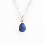 A silver pendant necklace featuring a faceted teardrop-shaped blue gemstone in a silver bezel setting, suspended from a delicate silver chain against a plain white background.