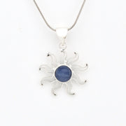 Silver sun-shaped pendant with a blue gemstone on a white background
