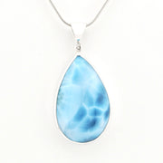 A teardrop-shaped pendant necklace featuring a light blue marbled gemstone in a silver bezel setting, suspended from a silver snake chain against a plain white background.