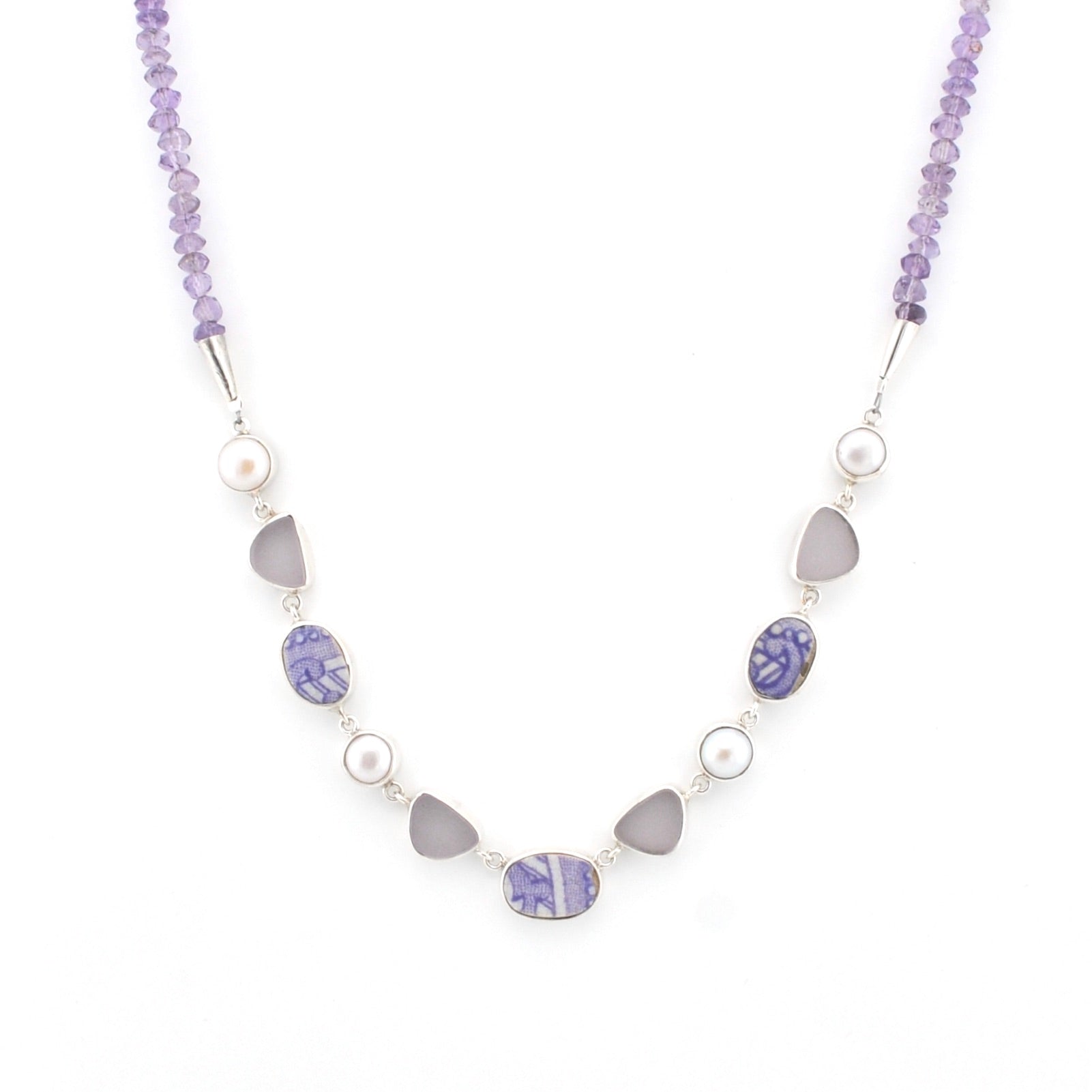 A beaded necklace featuring light purple amethyst beads, white pearls, and gray sea glass pieces set in silver-tone metal, displayed on a clean white background.