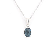 A silver chain necklace with an oval faceted dark blue gemstone pendant, shown against a plain white background.