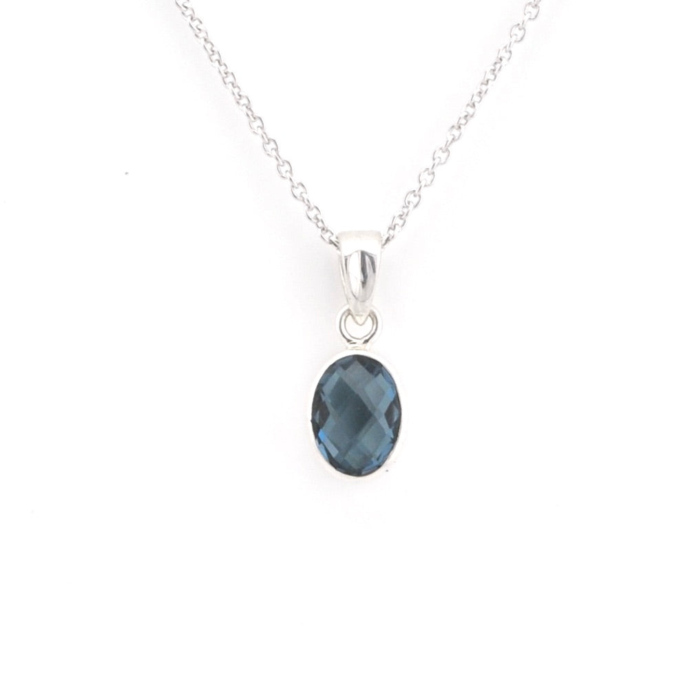 A silver chain necklace with an oval faceted dark blue gemstone pendant, shown against a plain white background.