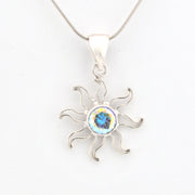 Silver sun-shaped pendant with a blue gemstone on a white background