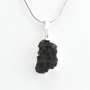 A raw moldavite pendant necklace on a silver chain, shown against a plain white background.