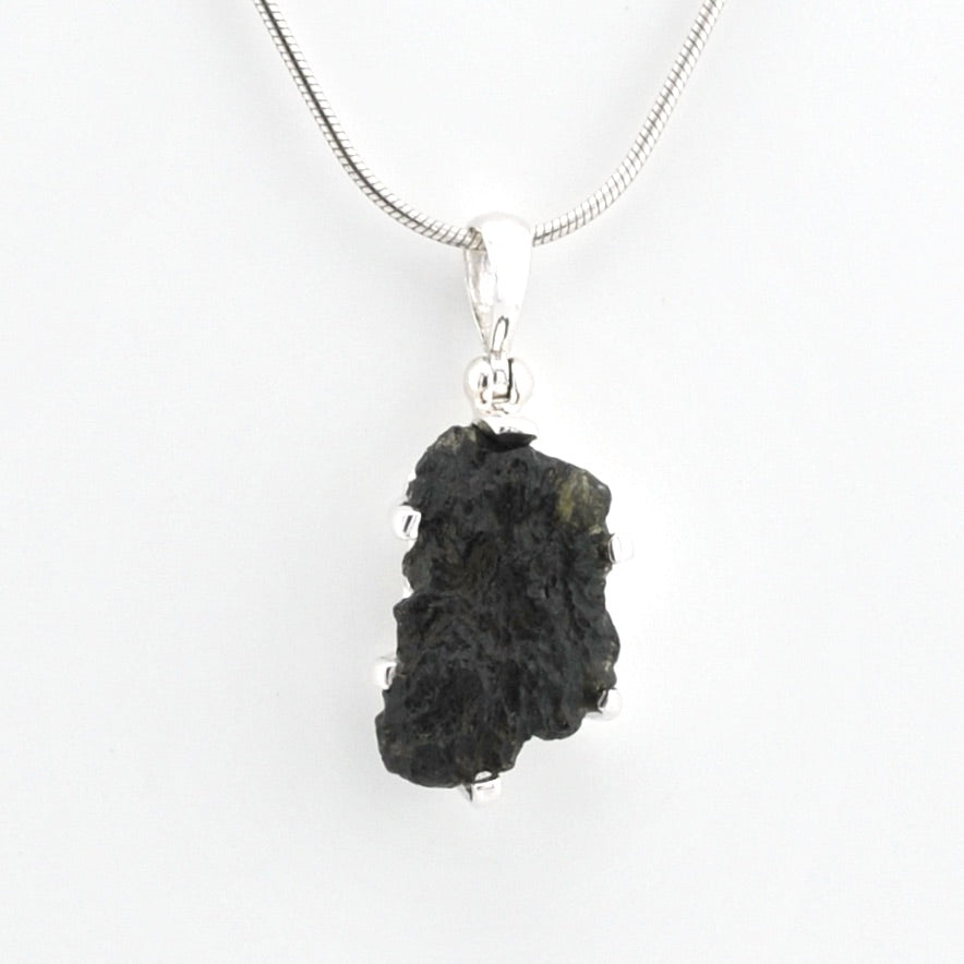 A raw moldavite pendant necklace on a silver chain, shown against a plain white background.
