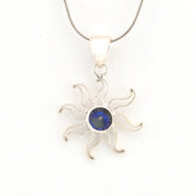 Silver sun-shaped pendant with a blue gemstone on a white background