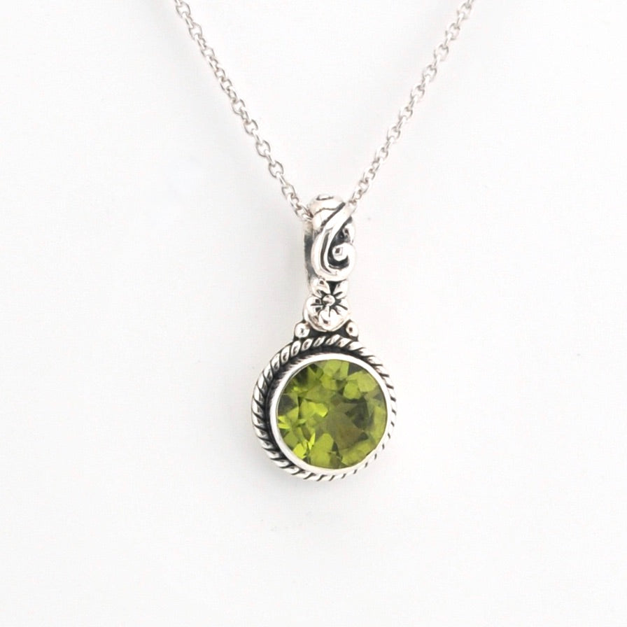 Silver necklace with a green gemstone pendant on a white background