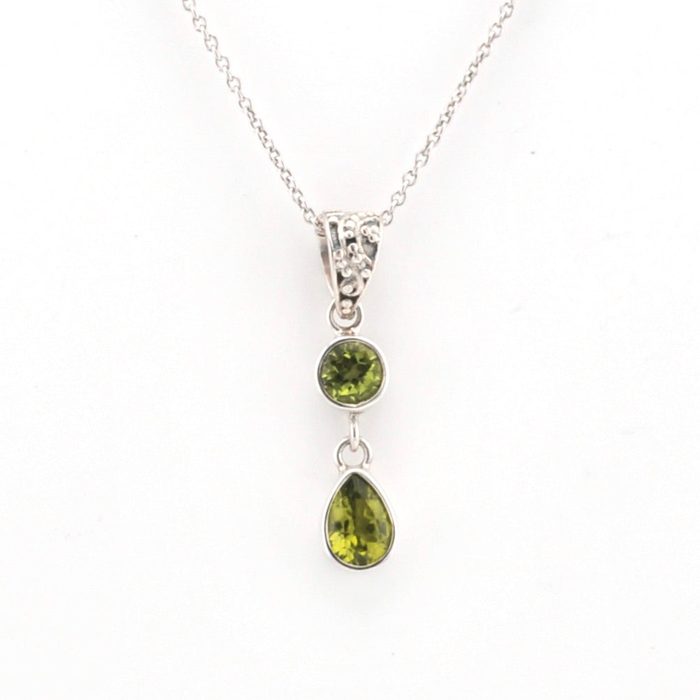Silver necklace with two green gemstone pendants on a white background