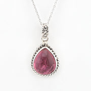 A silver pendant necklace featuring a teardrop-shaped pink gemstone in a textured silver bezel setting, suspended from a delicate silver chain against a plain white background.