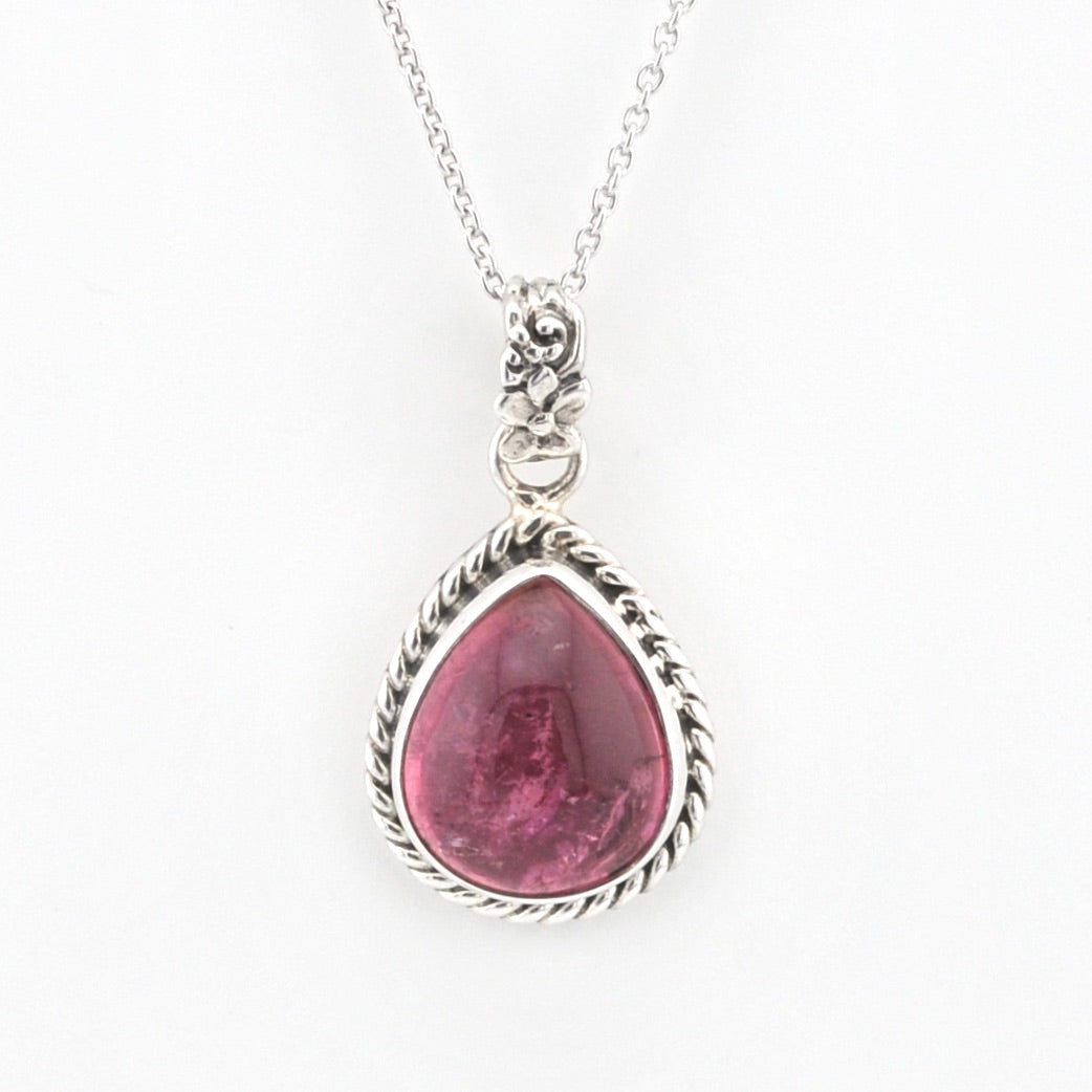 A silver pendant necklace featuring a teardrop-shaped pink gemstone in a textured silver bezel setting, suspended from a delicate silver chain against a plain white background.