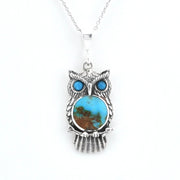 A sterling silver owl pendant necklace featuring a round turquoise stone with brown matrix inlay and two smaller blue turquoise stones for eyes, suspended from a silver chain on a white background.