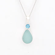 Teardrop-shaped light blue pendant with a blue gemstone on a white background