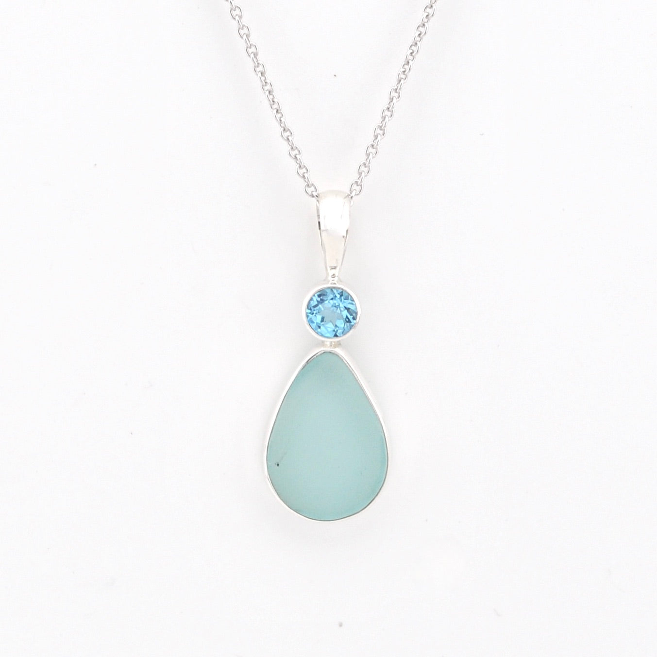 Teardrop-shaped light blue pendant with a blue gemstone on a white background