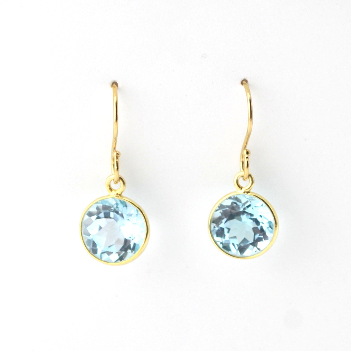 Gold earrings with blue gemstones on a white background