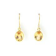 Gold earrings with citrine stones on a white background