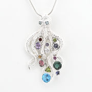 A silver octopus-shaped pendant necklace adorned with multiple colorful gemstones, suspended from a silver chain against a plain white background.