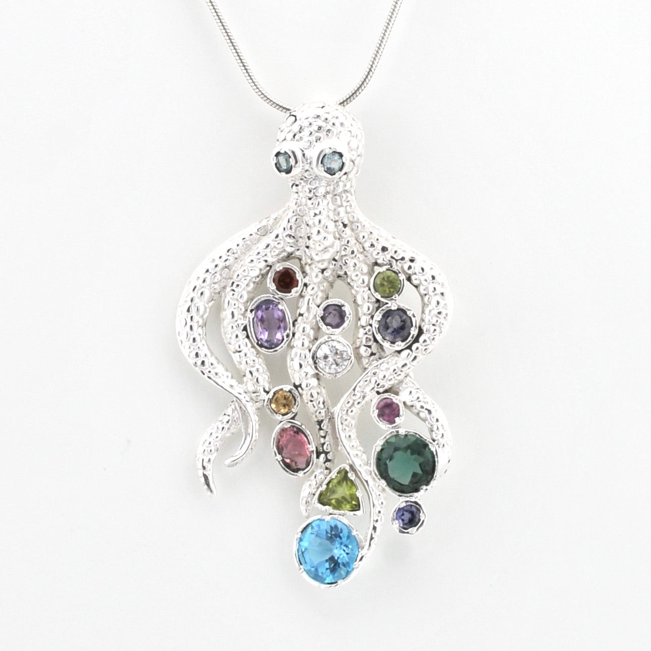 A silver octopus-shaped pendant necklace adorned with multiple colorful gemstones, suspended from a silver chain against a plain white background.