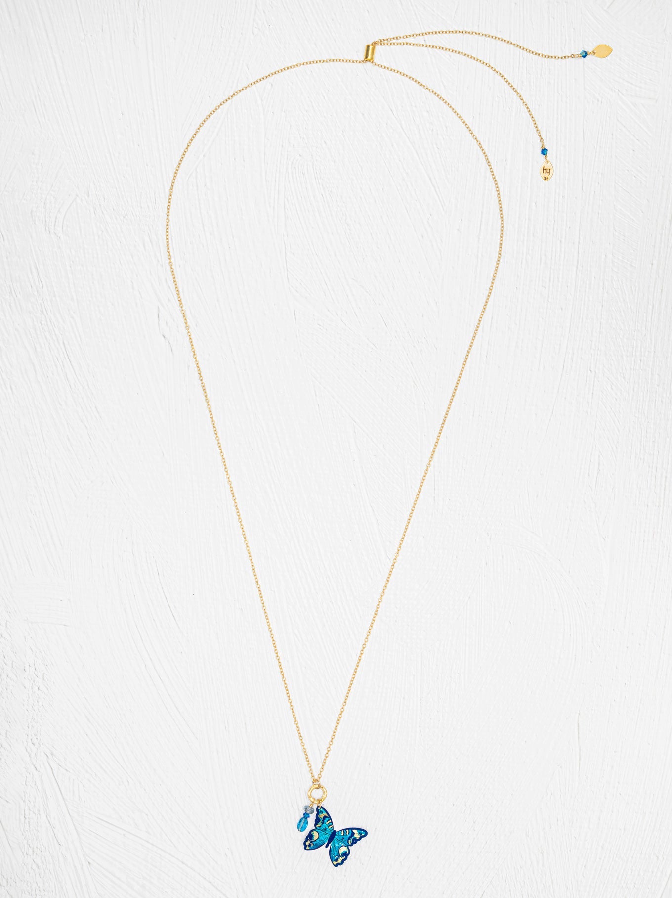 Gold necklace with a blue butterfly pendant on a white background