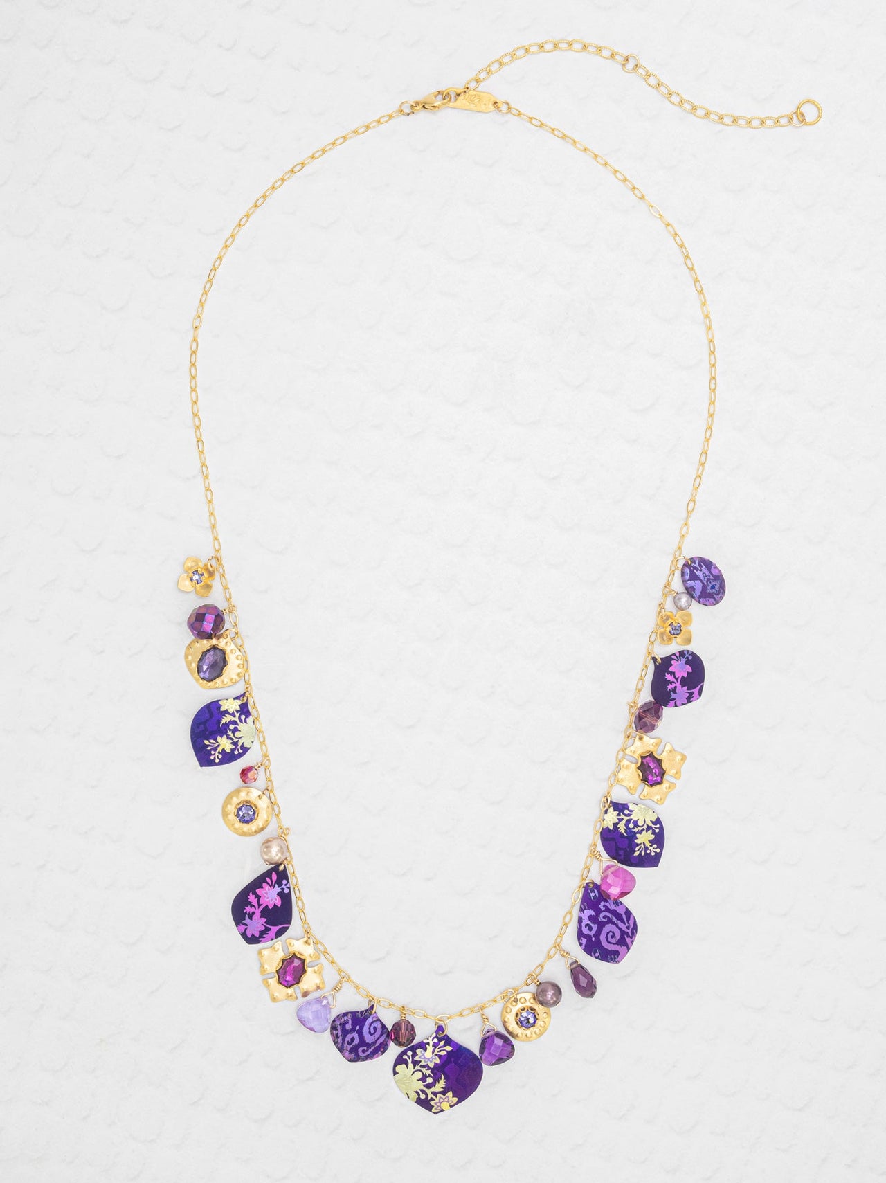Necklace with purple and gold beads on a light gray background
