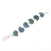 A sterling silver bracelet featuring six circular segments inlaid with vibrant blue and green turquoise, displayed on a clean white background.