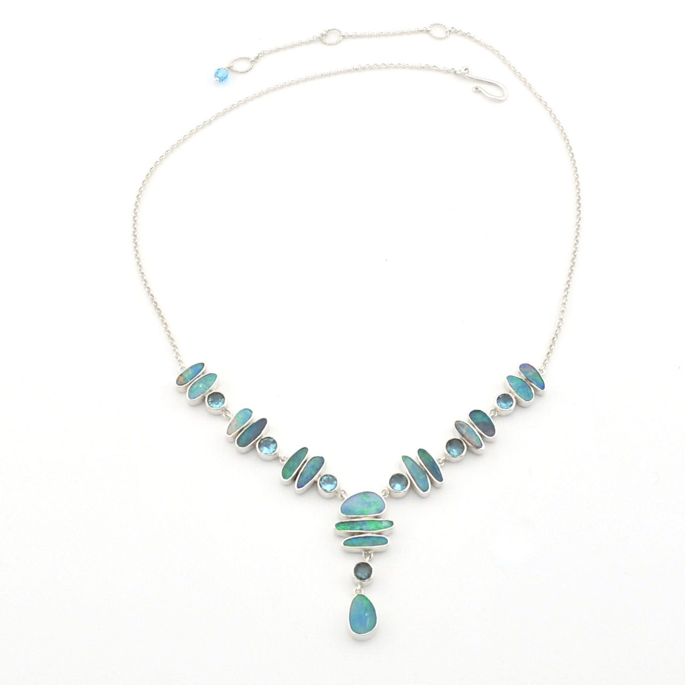 A silver necklace featuring a series of light blue and green opal set in silver, with a teardrop-shaped blue opal hanging at the center, displayed on a clean white background.