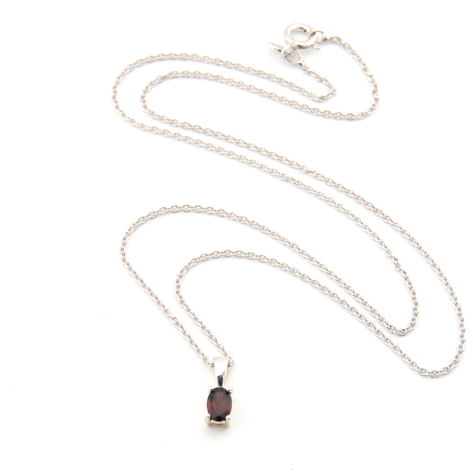 Silver necklace with a dark gemstone pendant on a white background
