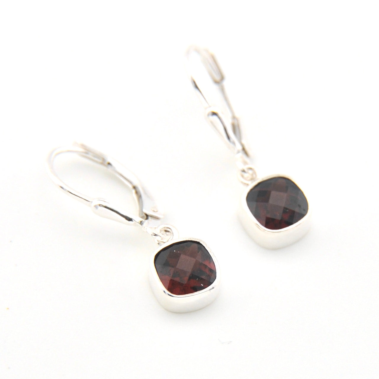 Silver earrings with garnet gemstones on a white background