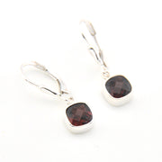 Silver earrings with garnet gemstones on a white background